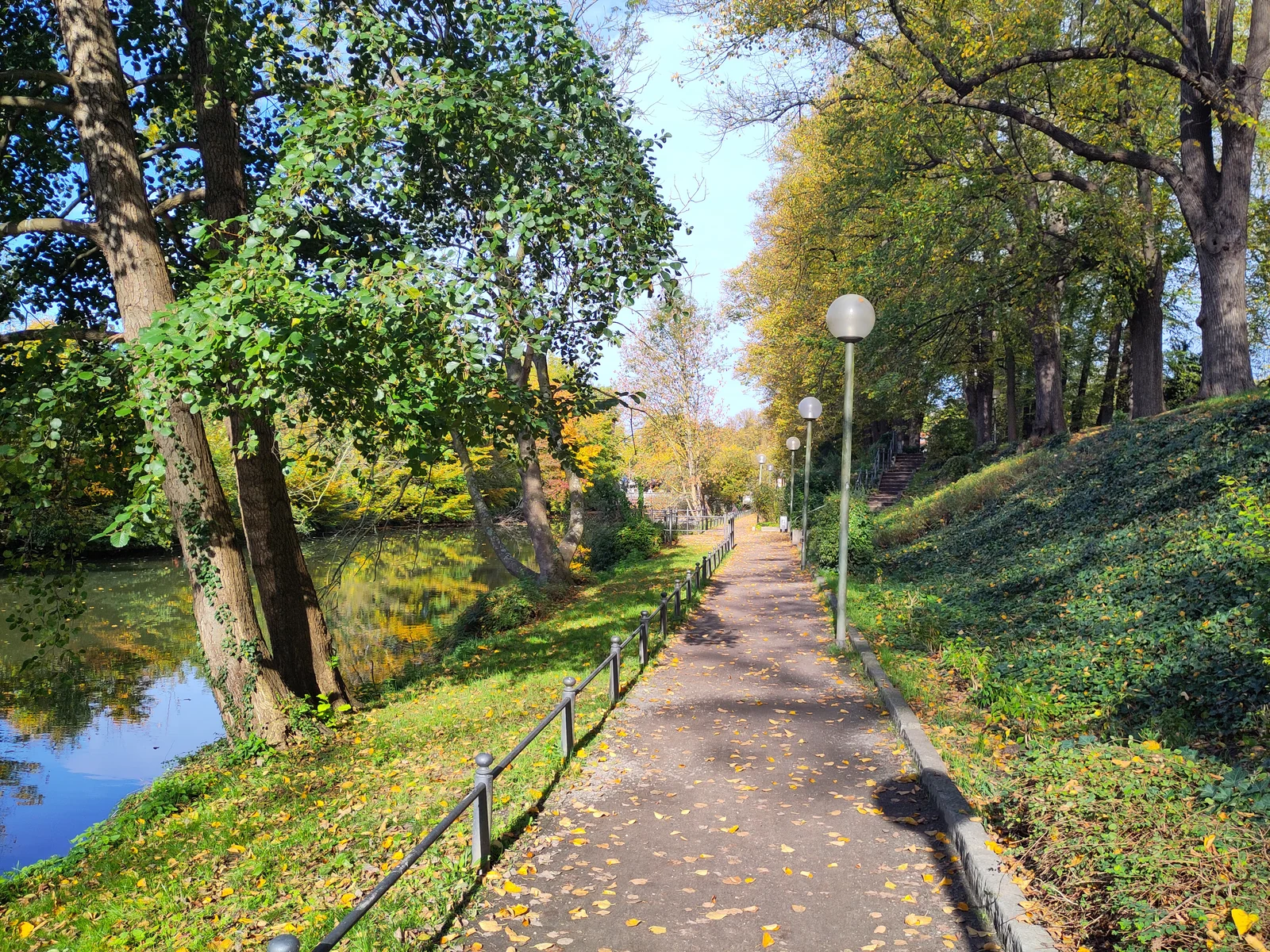 Quiet riverside path and pedestrian bridge under autumn foliage